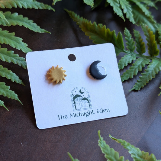 Sun and moon earrings on a 'The Midnight Glen' branded card with fern leaves in the background