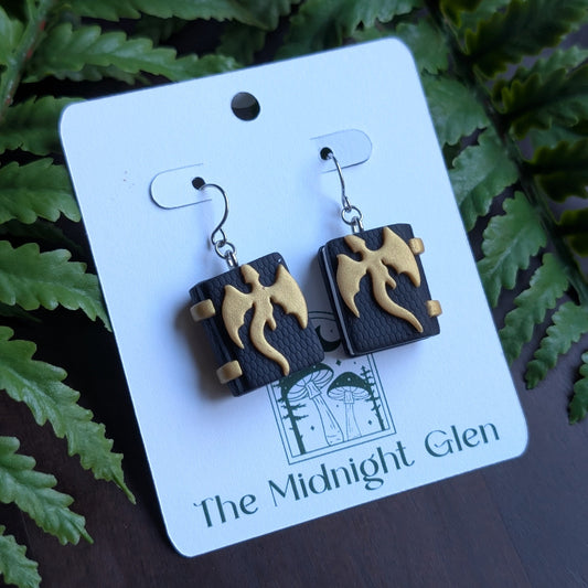 Pair of earrings on a card with 'The Midnight Glen' branding against a fern background